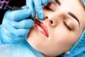 Cosmetologist making permanent makeup on woman's face